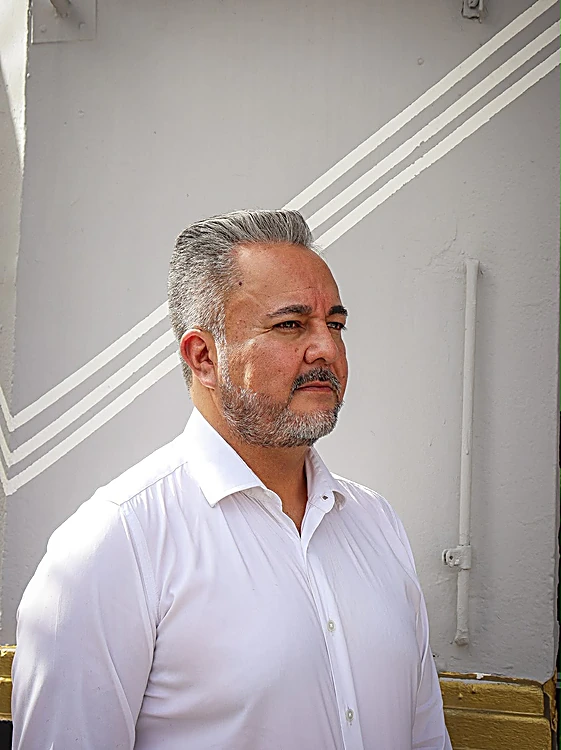 Cliente con canas, peinado hacia atrás y barba corta, frente al muro rayado.